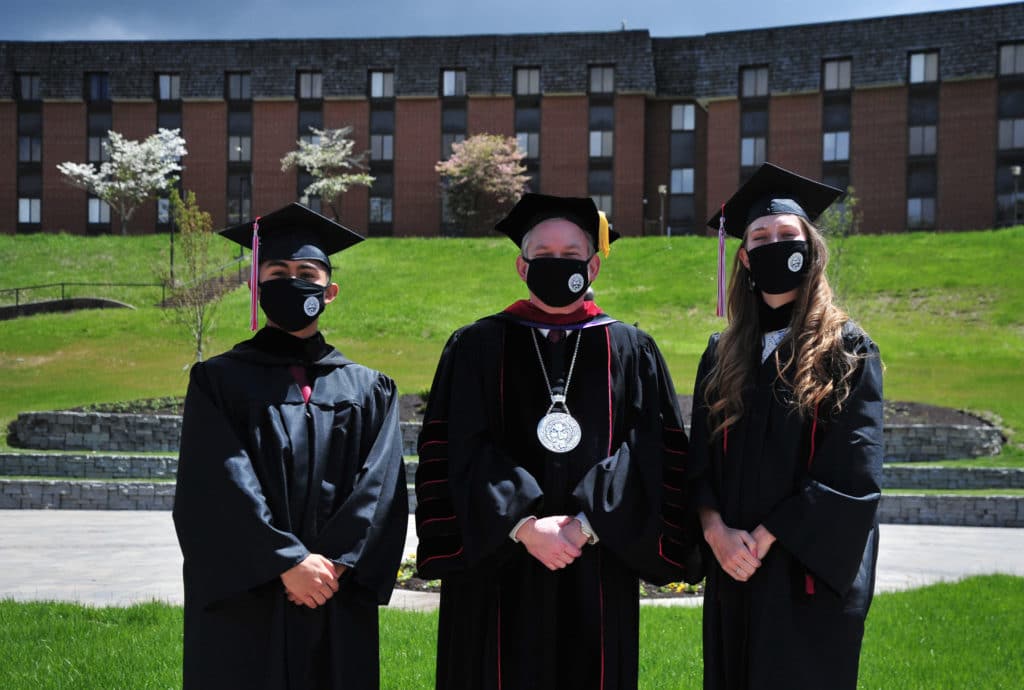 Davis & Elkins College Class of 2021 Valedictorian Samantha Kirk and Salutatorian Geovani Steven Ibarra, left, prepare to enter the Commencement Ceremony with D&E President Chris A. Wood.