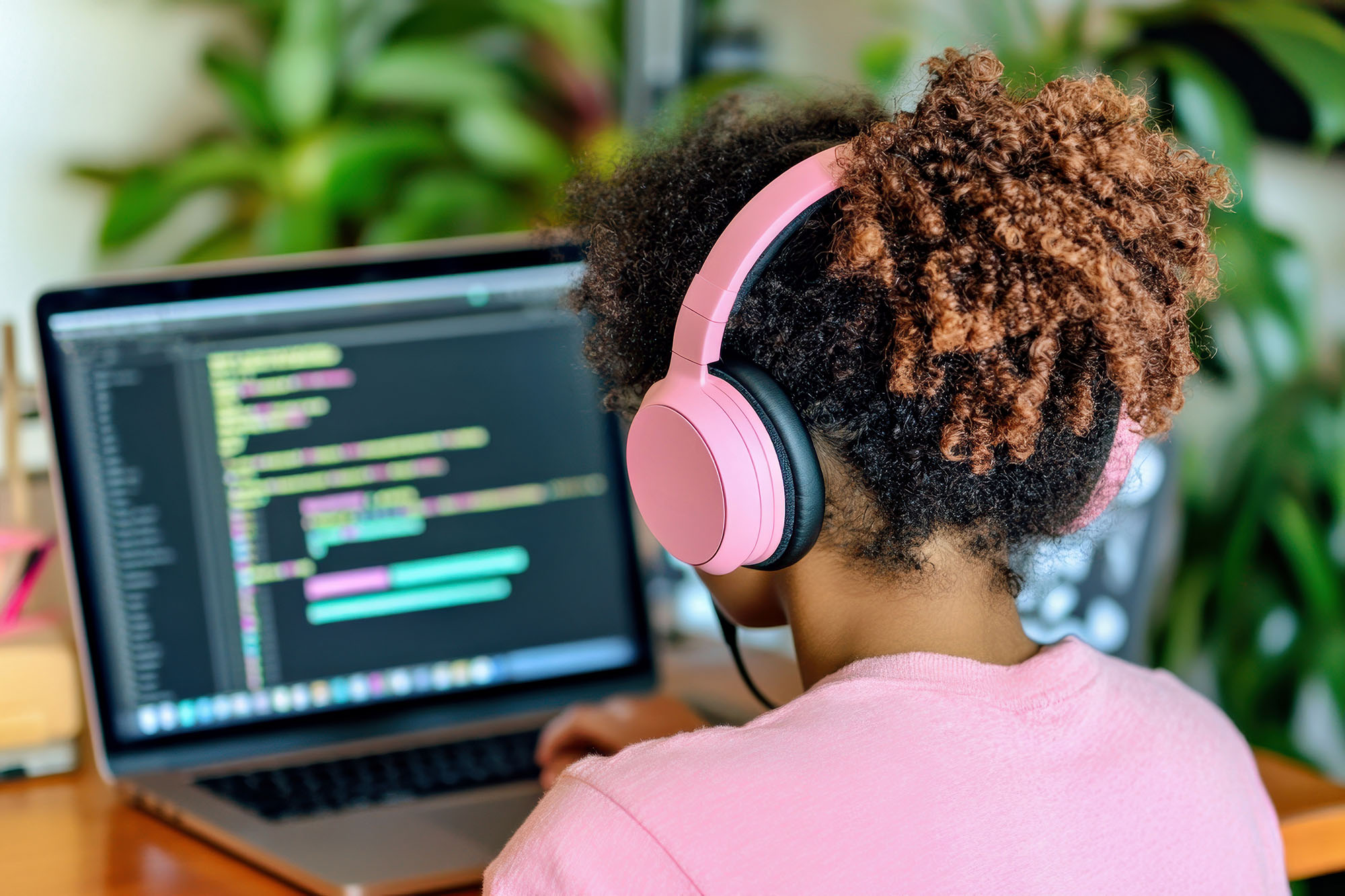 Female college student seen from behind coding on a laptop