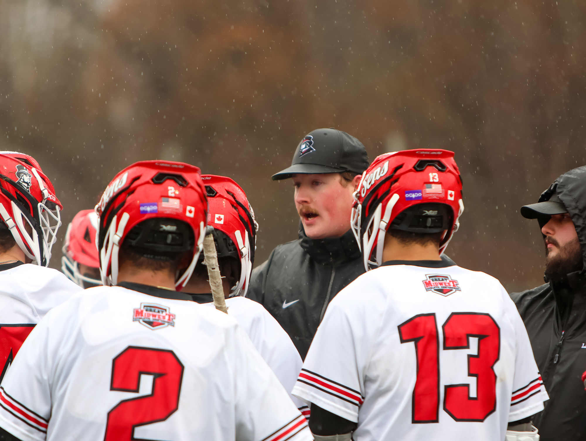 Coach Allan talks to the men's lacrosse team during a break in the game.